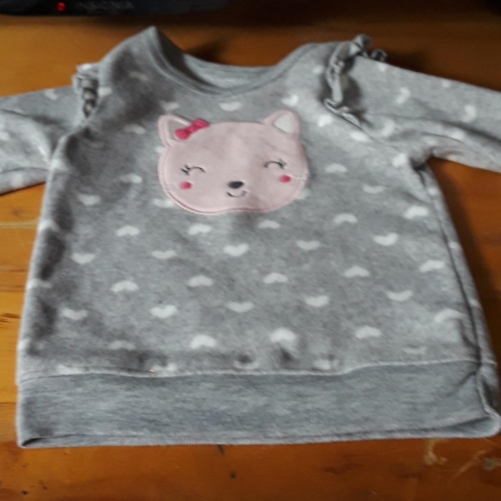 A baby sweater with a cat face on it